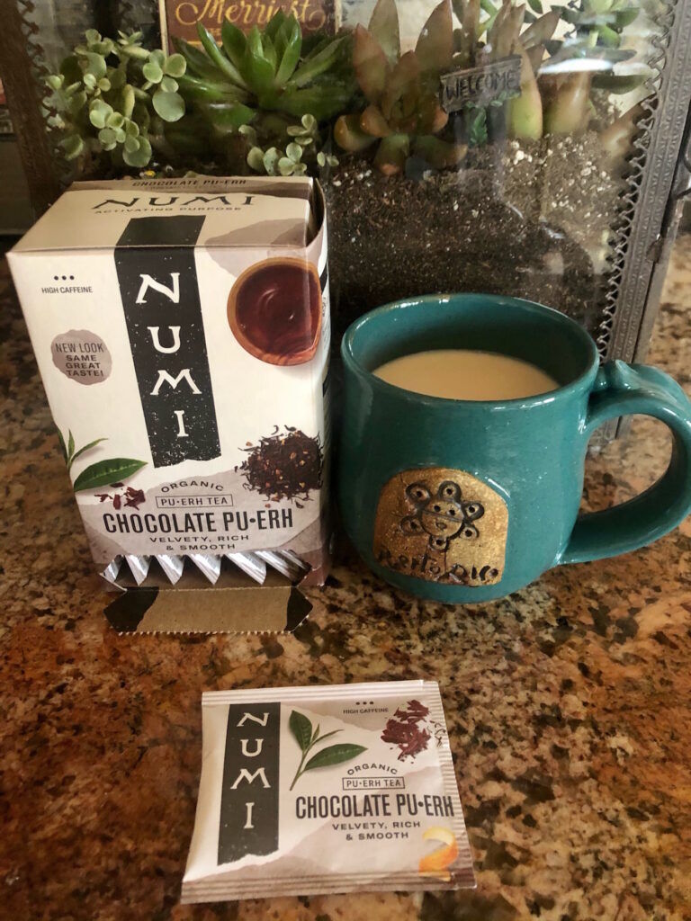 Cup of Numi Chocolate Pu-erh with the tea package and individual packet
